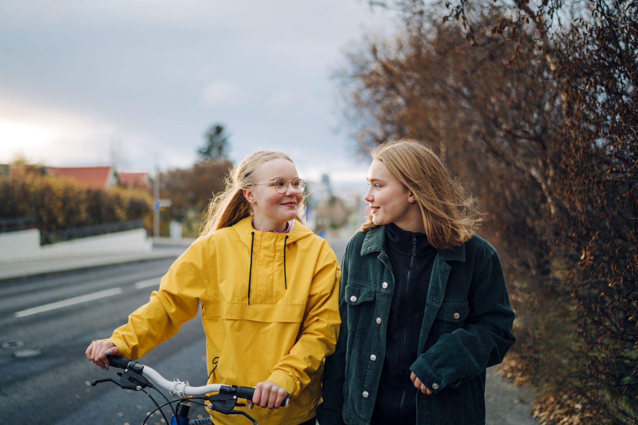 Två tonårstjejer på promenad med en cykel, foto. 