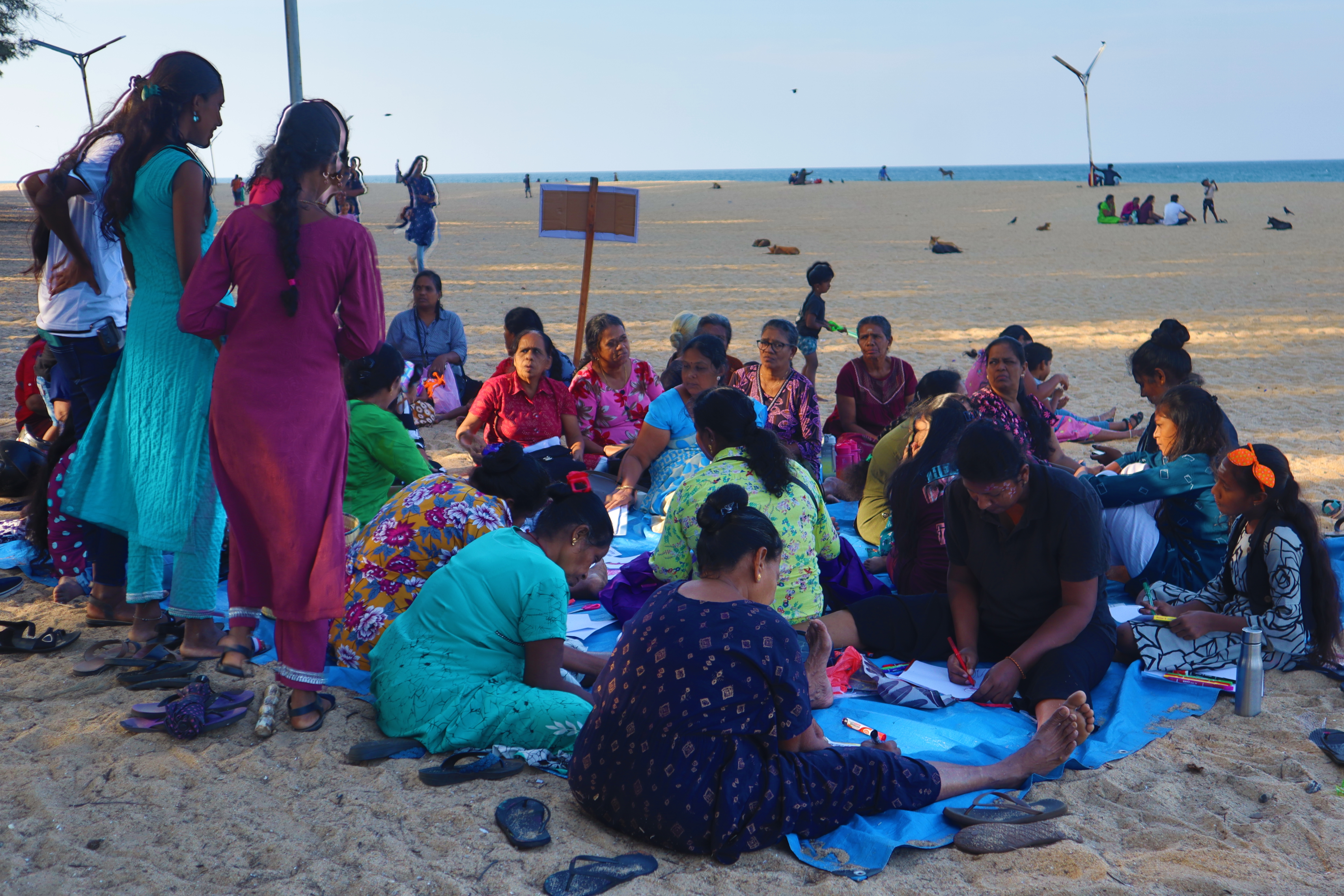 People drawing on a blanket at the beach 