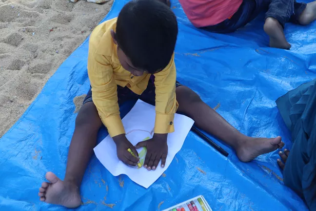 Child drawing at the beach 
