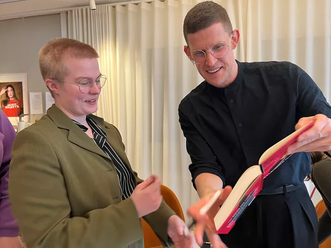 Kalle Norwald signerar ett exemplar av sin bok åt Oscar Viklund från RFSU Umeå 